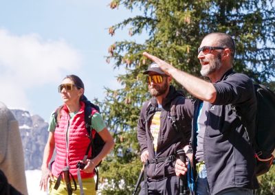 Persone in montagna che indicano il panorama con sullo sfondo abeti