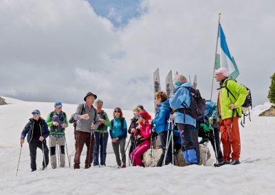 Persone in montagna in inverno con panorama innevato e guida che spiega